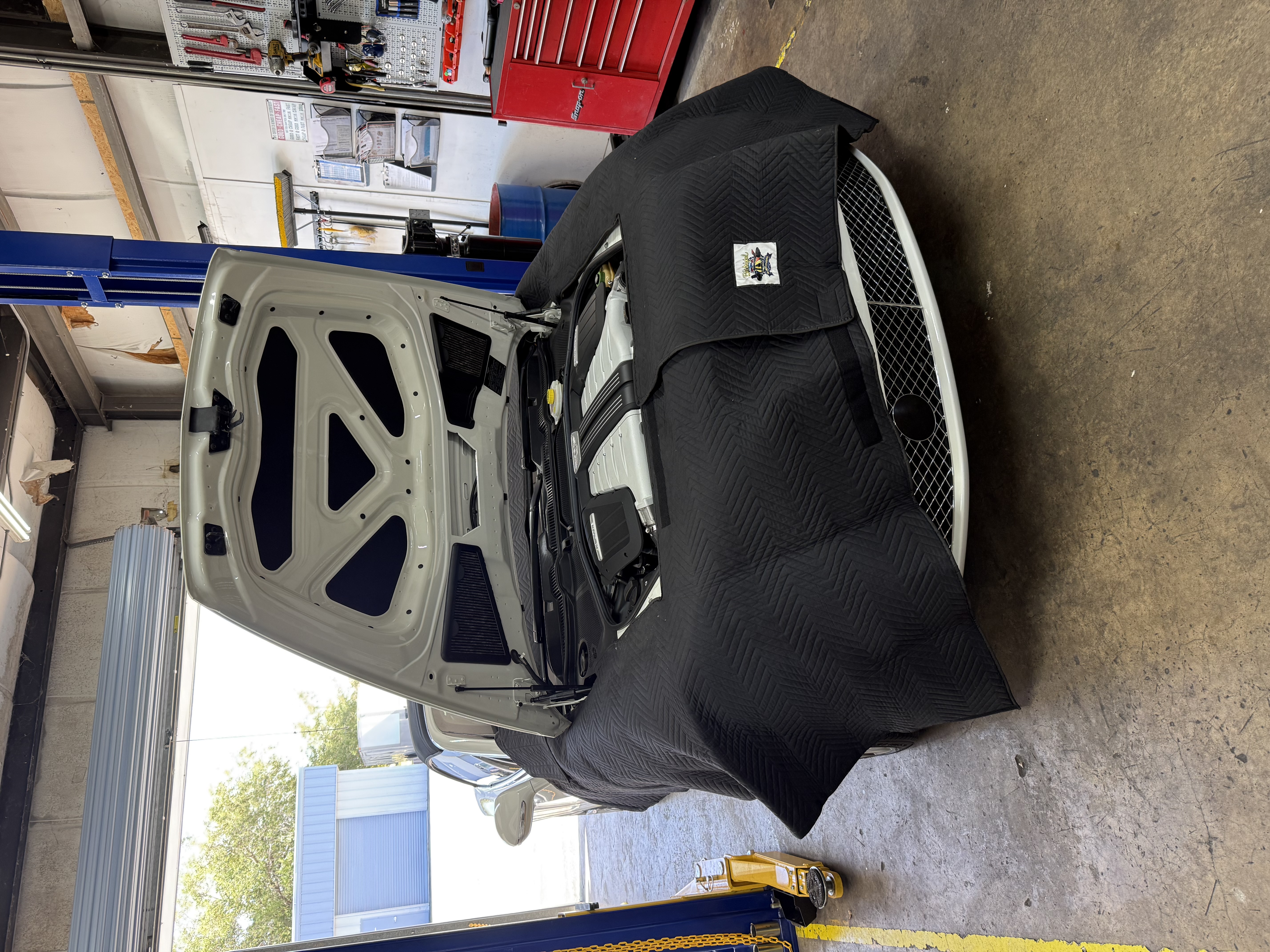 Bentley with the hood open and protective quilted covers over its bodywork at Dolan’s Garage